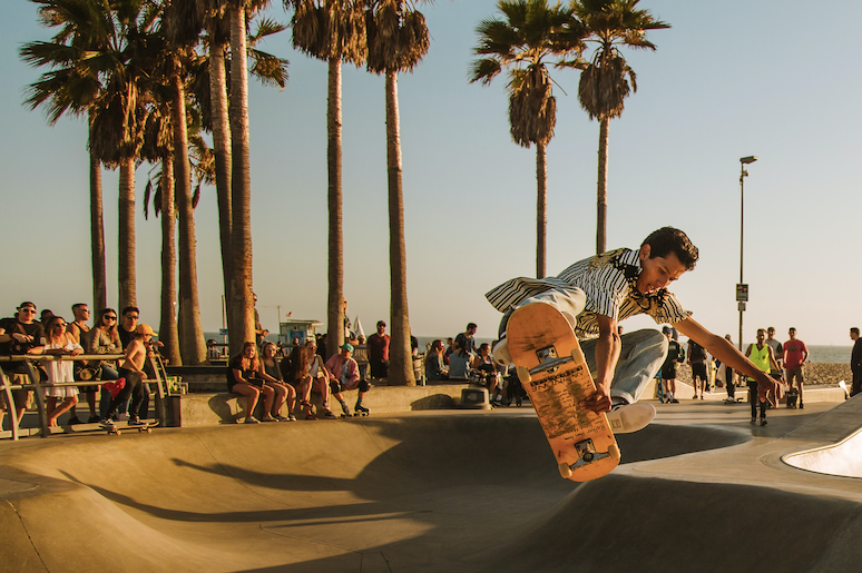 Young man skate boarding at Venice Beach in summer getting some air. 